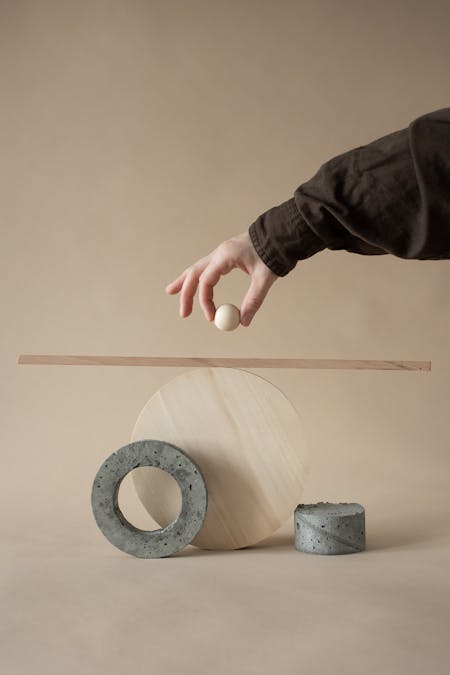 Person Holding a Ball Over a Composition From Concrete and Wooden Shapes