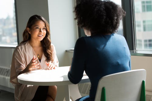 two women sitting at table talking