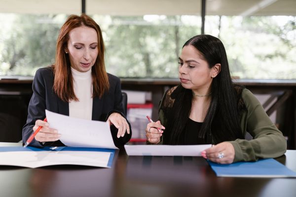 Two professional women reviewing documents in a well-lit office setting